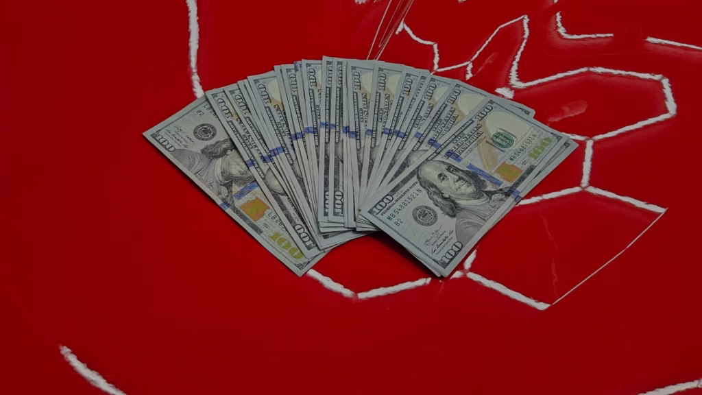 Cash on red corvette showing the value of professional detailing, paint correction, and protecting your vehicle investment