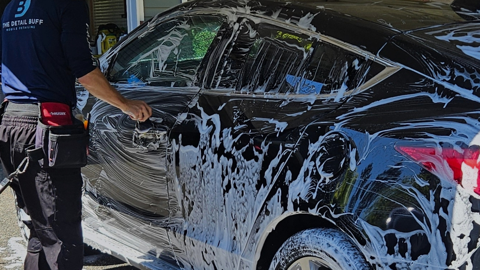 professional detailer using straight-line hand-washing technique on vehicle paint